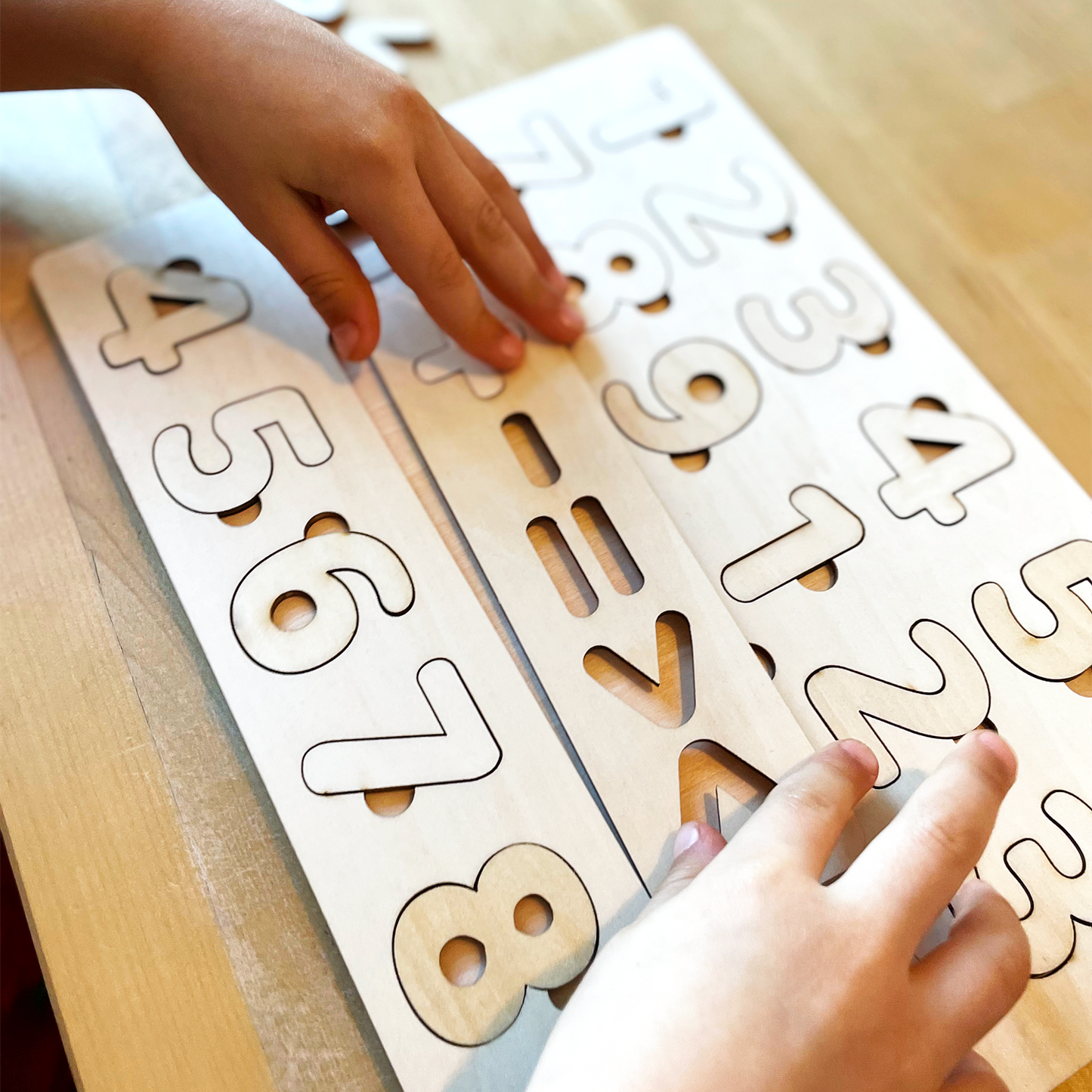 Kinderhänder benutzen eine Holztafel mit herausnehmbaren Zahlen.